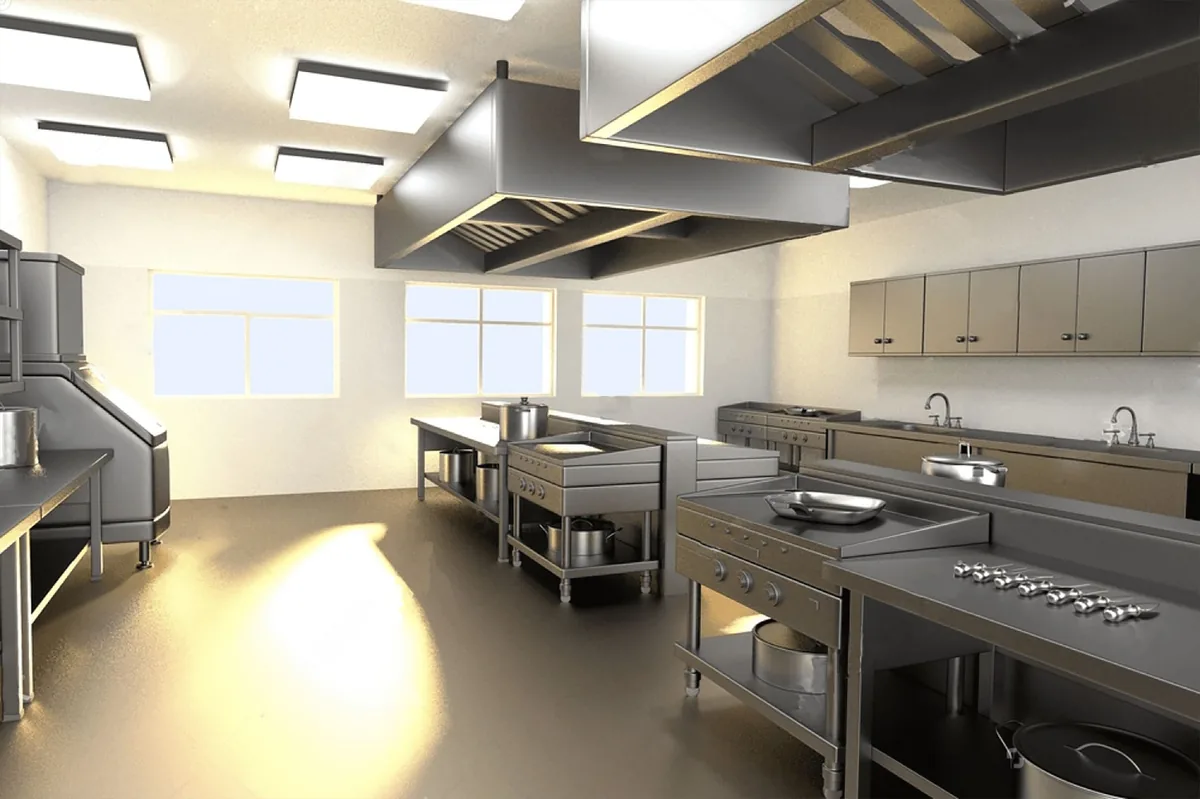 Cocina de acero con luz natural que entra por tres ventanas y campanas de gran tamaño colgadas del techo