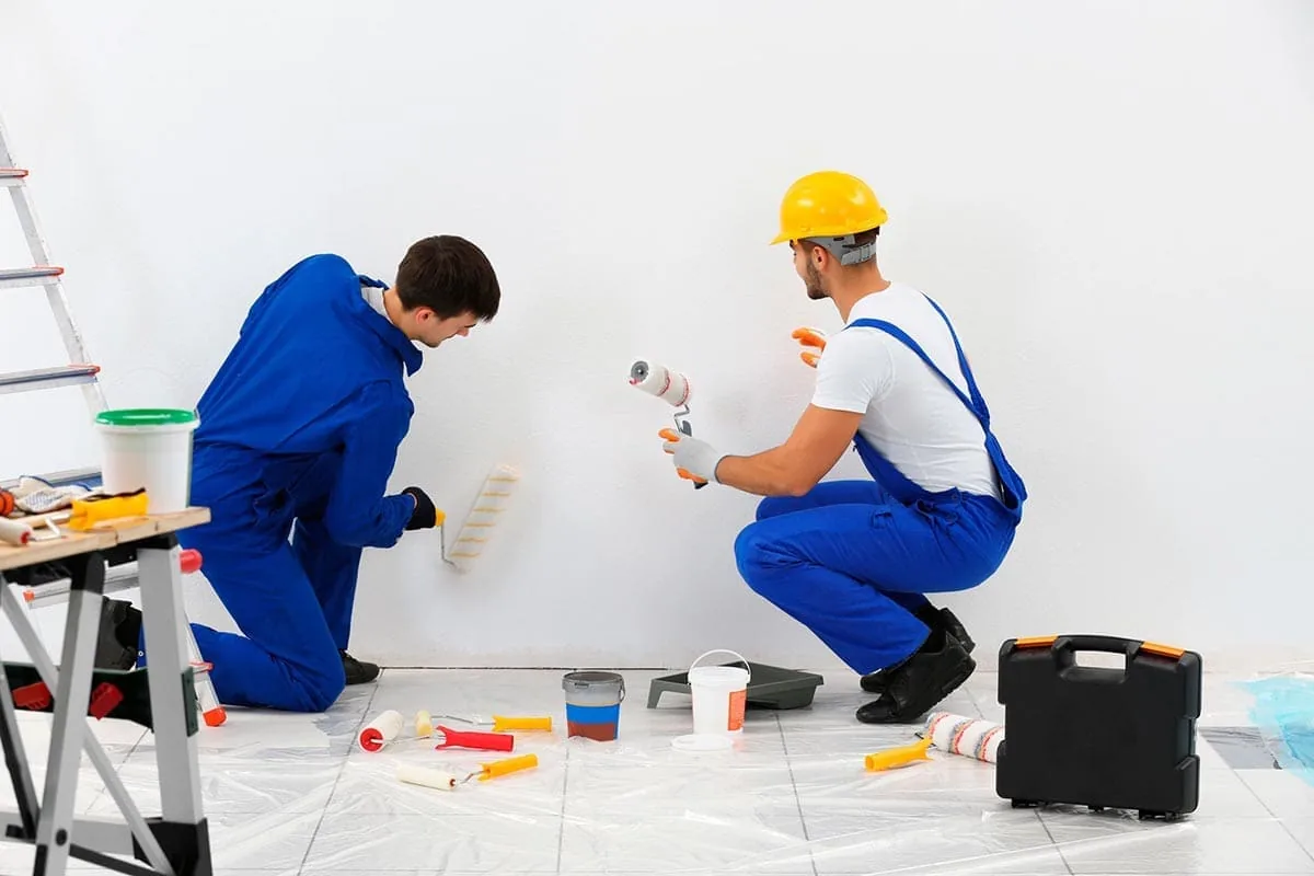 Pintor de espaldas pintando una pared blanca en el interior de una casa