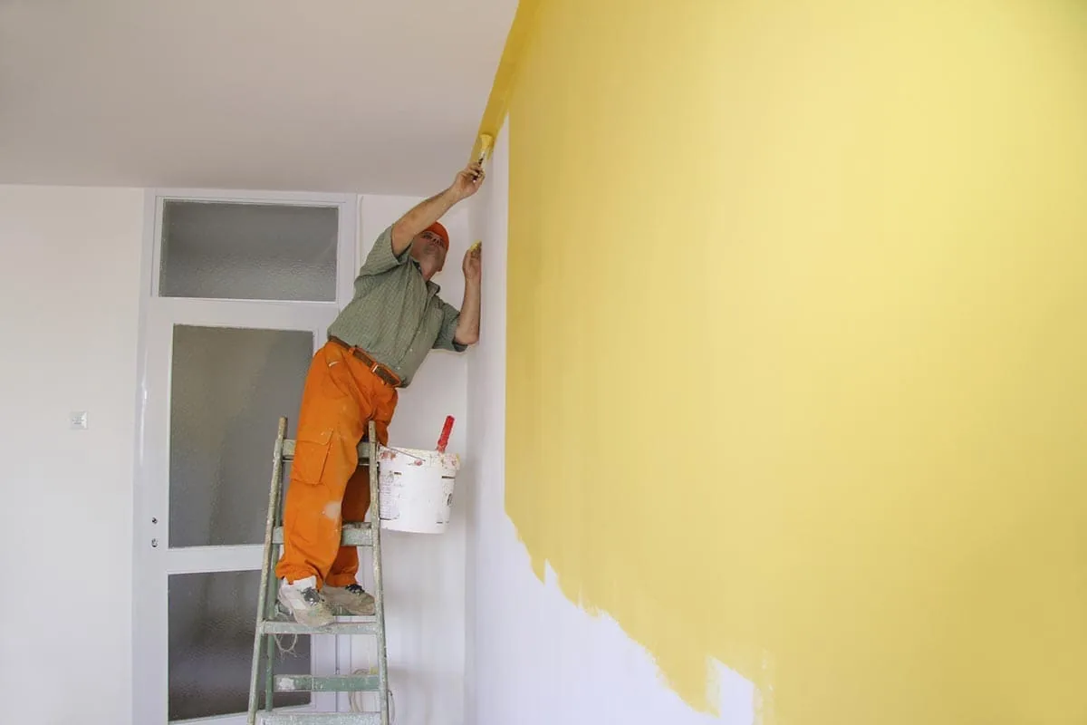 Pintor trabajando en una pared interior de una vivienda