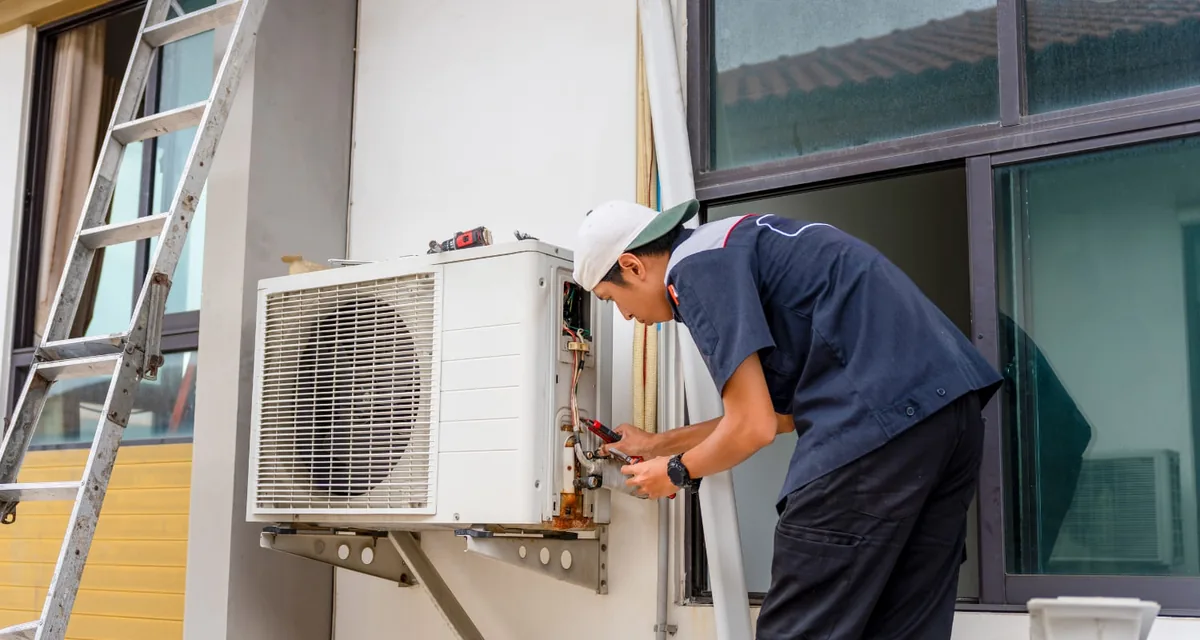 Técnico fijando un equipo de aire acondicionado split en la pared durante una instalación