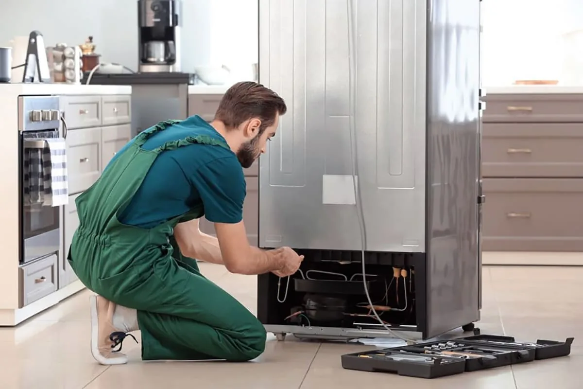 Técnico de servicio trabajando en un frigorífico averiado