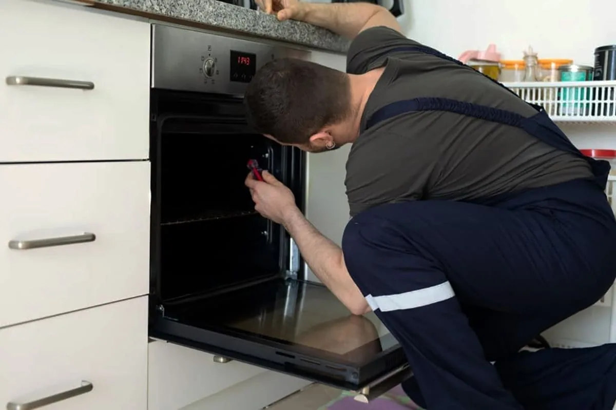 Técnico revisando un horno durante una reparación a domicilio en Elche