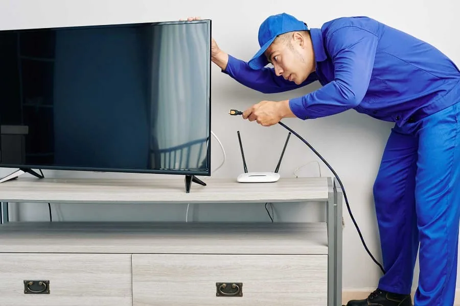Técnico con herramientas de precisión desmontando un televisor averiado