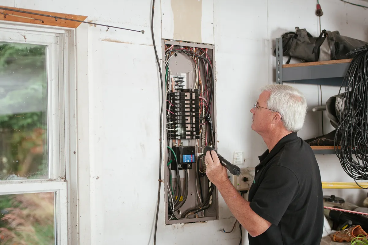 Electricista examinando con atención la caja de fusibles de una vivienda