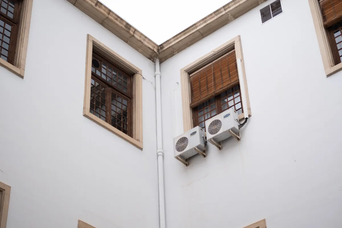 Fachada blanca con persianas de madera y unidades de aire acondicionado