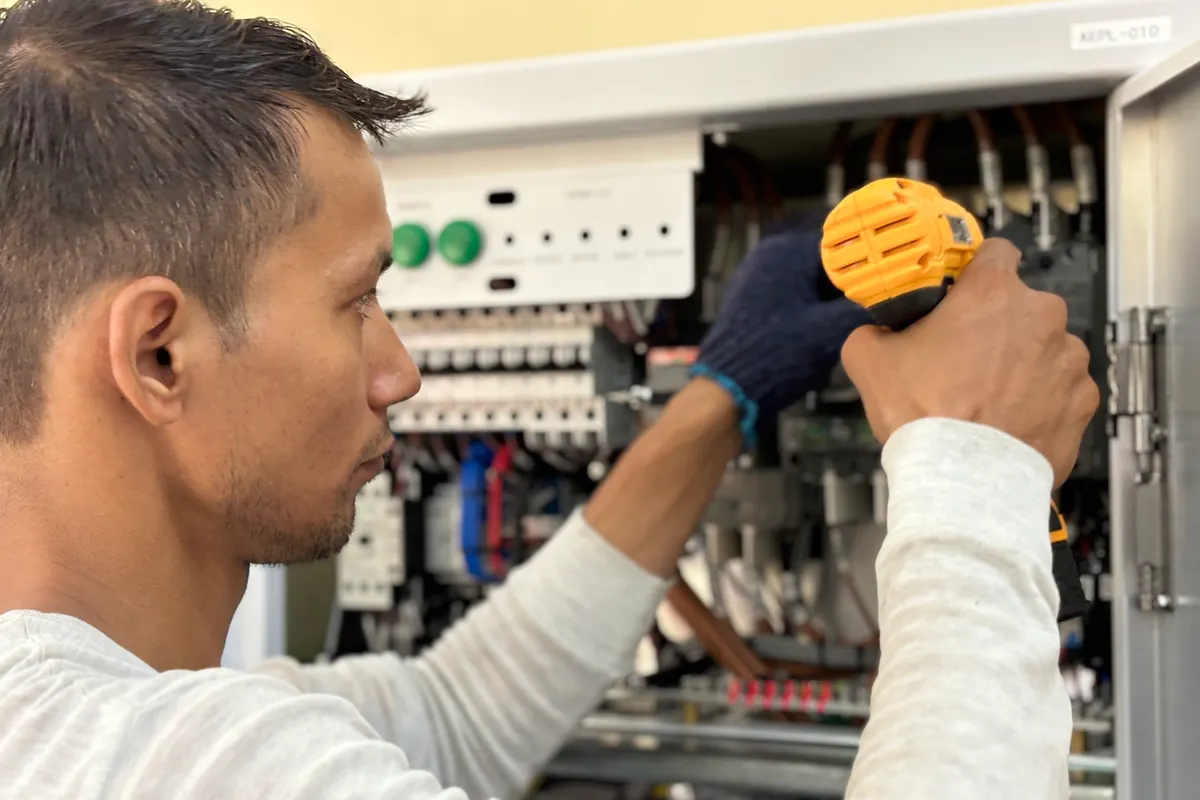 Técnico concentrado usando un taladro sobre un cuadro eléctrico